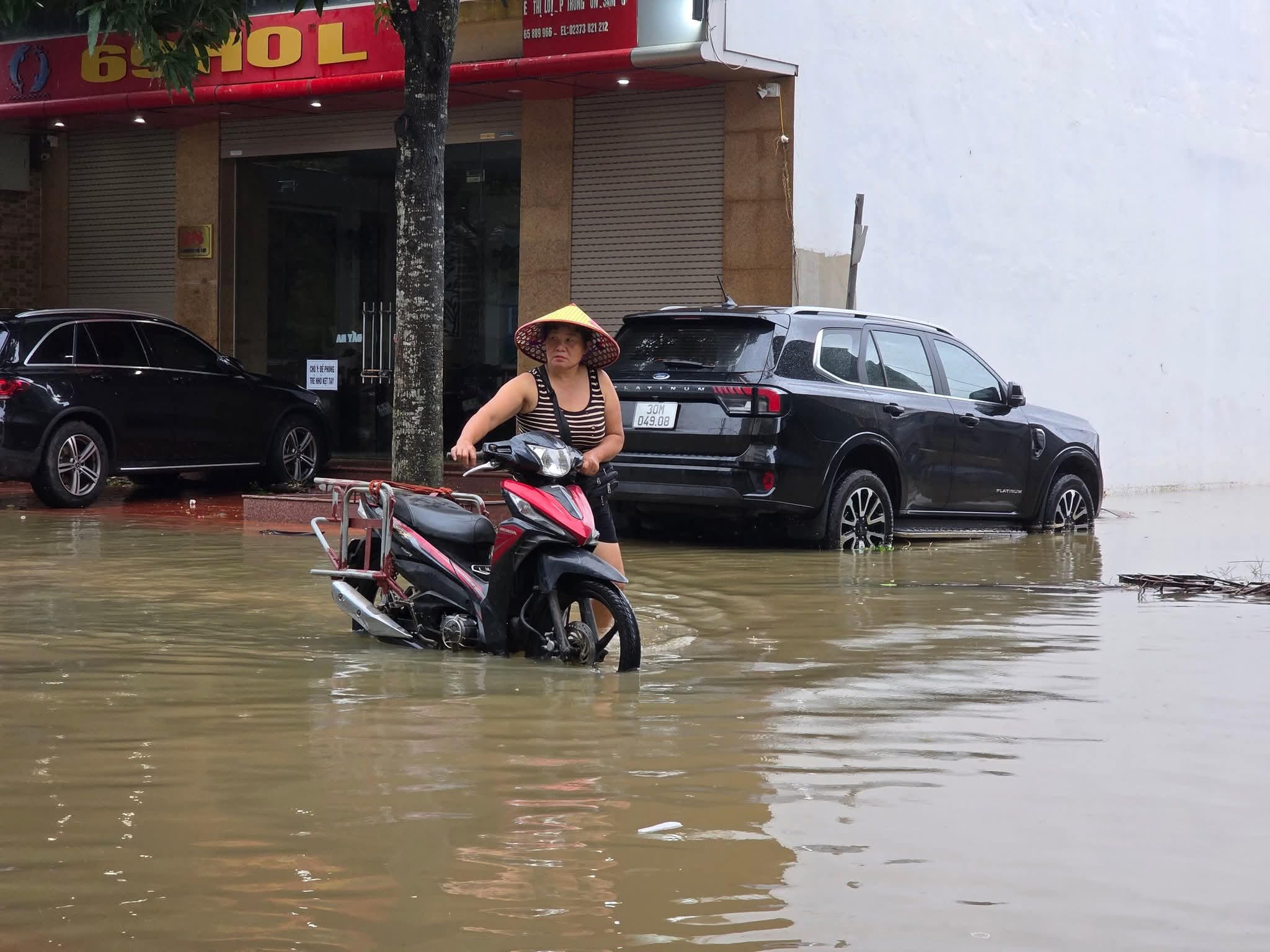 Người dân phường ven biển Sầm Sơn dắt xe máy qua khu vực bị ngập. Ảnh: Hà Anh.