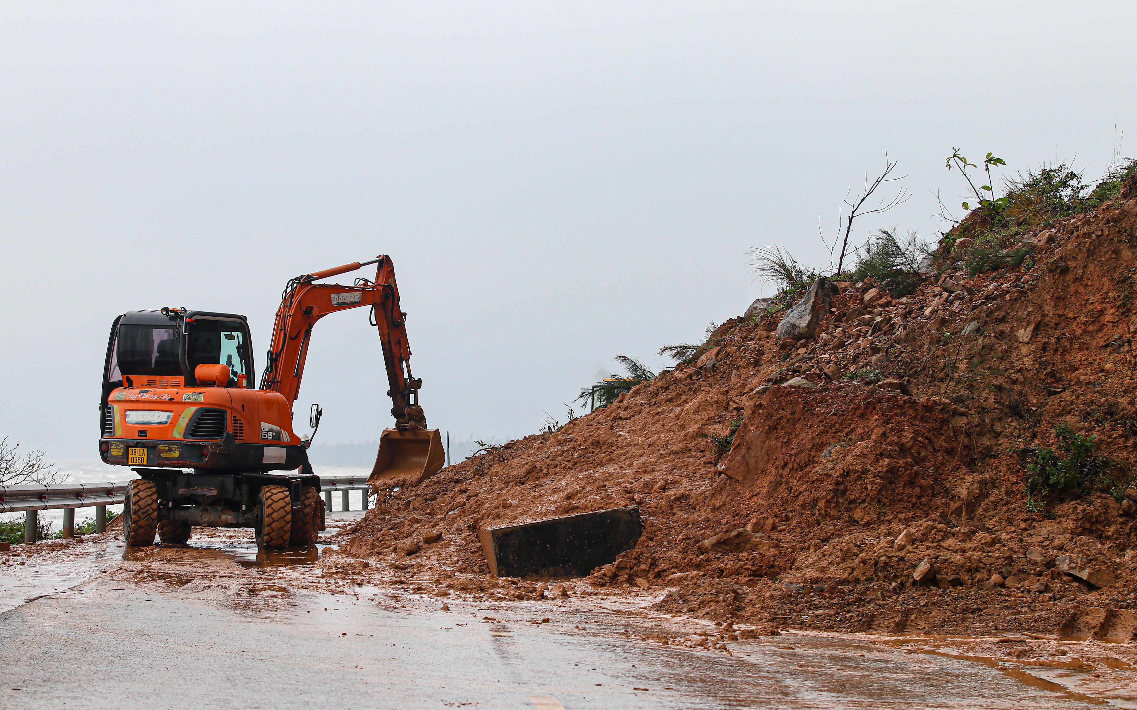 Đơn vị quản lý tuyến đường đã huy động máy xúc, xe ben, công nhân kỹ thuật khẩn trương thu dọn đất đá để sớm khôi phục giao thông. Ảnh: Cẩm Kỳ