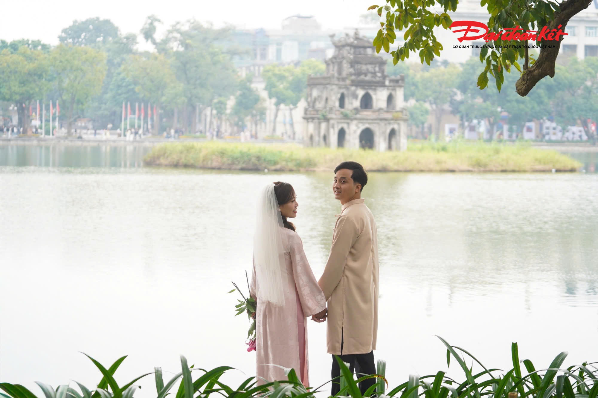 Nhiều cặp đôi tay trong tay mặc áo dài chụp ảnh ở Hồ Gươm.