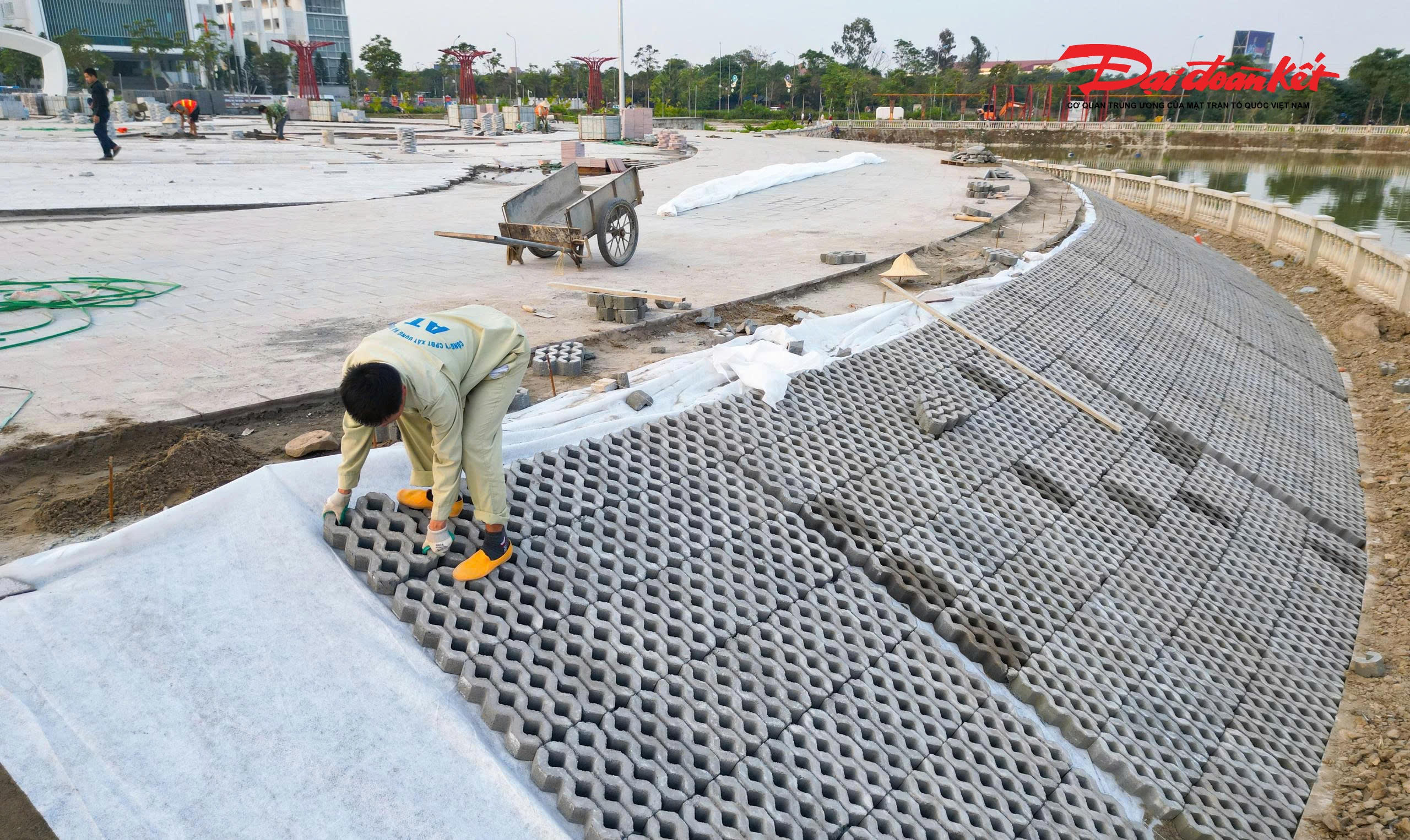 Hình ảnh công nhân đang tiến hành lắp đặt bờ kè sát phía hồ.