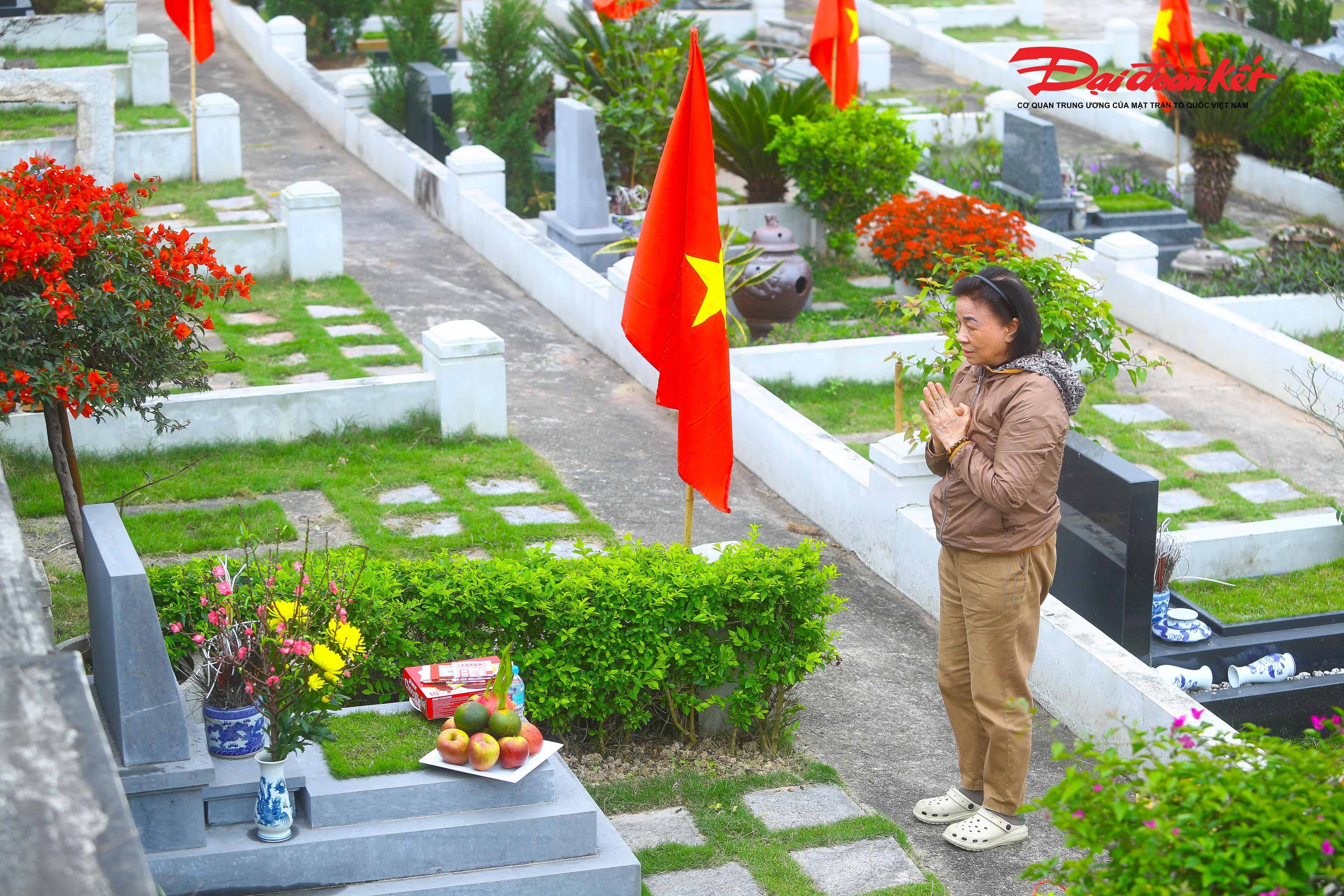 Bà Thi chọn một cành đào nhỏ đặt trước phần mộ loài hoa mà khi còn sống, chồng bà yêu thích nhất. Bà vẫn nhớ rõ, chồng mình chỉ thích đào, đặc biệt là những cành đào vùng núi Tây Bắc, thứ mà mỗi dịp Tết đến ông đều tự tay đi chọn mua. Đứng lặng trước mộ, bà khe khẽ thủ thỉ đủ chuyện trong gia đình, từ con cái đến những dự định sắp tới, như thể người bạn đời năm nào vẫn đang hiện hữu, lặng lẽ lắng nghe từng lời tâm sự.