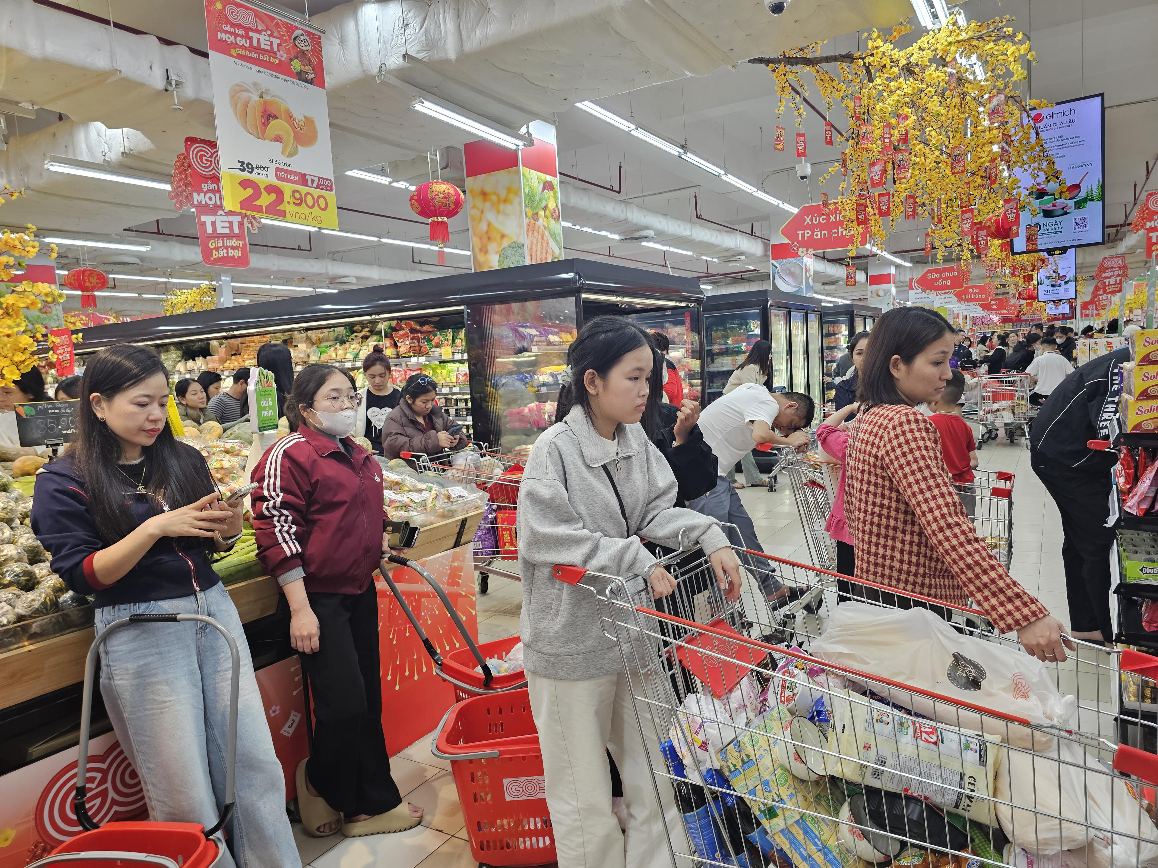 Nhiều khách hàng tranh thủ lướt smartphone trong lúc chờ đợi thanh toán. Sự sôi động tại các trung tâm thương mại còn góp phần làm cho không khí Tết thêm rõ nét, rộn ràng.&nbsp;Ảnh: Quốc Thanh.